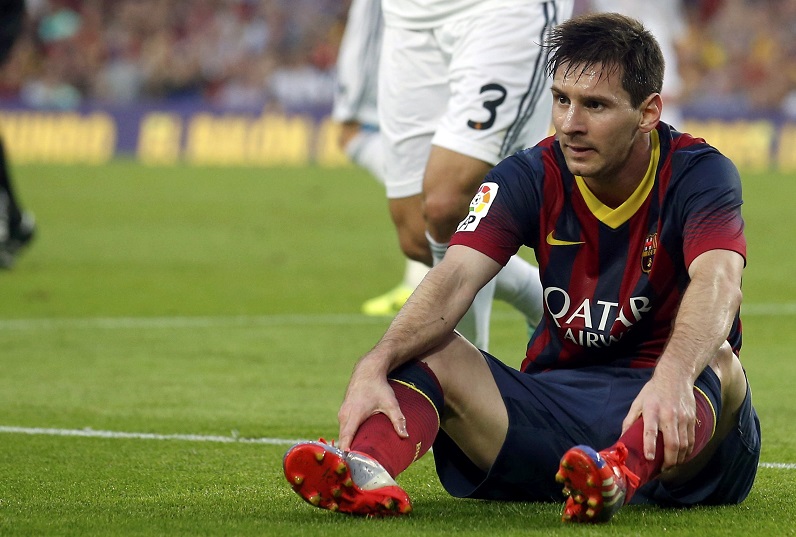 Barcelona's Messi sits in the pitch as Real Madrid's Pepe argues in the background during their Spanish first division 