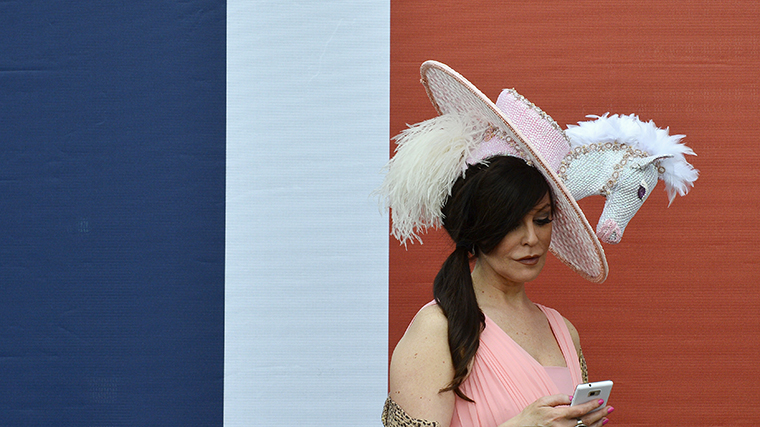 A racegoer wearing an equine themed hat checks her phone on the first day of the Royal Ascot horse racing festival at Ascot in southern England